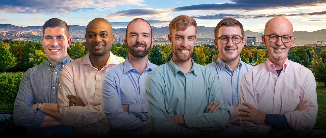 A group photo of Peters Patchin & Monaghan standing in front of a scenic background featuring a park with trees and a city skyline with mountains in the distance.