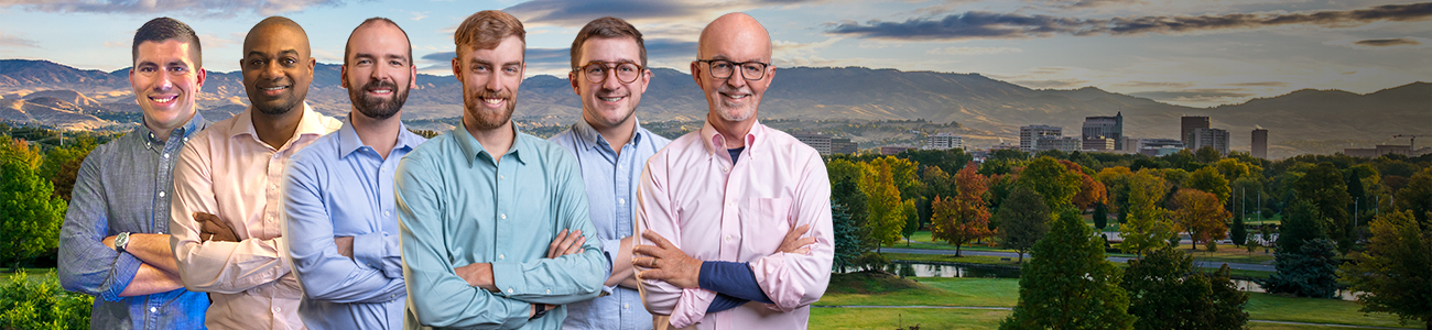 A group photo of Peters Patchin & Monaghan standing in front of a scenic background featuring a park with trees and a city skyline with mountains in the distance.